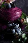 Nahaufnahme von Haufen reifer Blaubeeren in Schüssel, serviert auf schwarzem Tisch mit violettem Tuch — Stockfoto