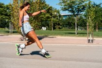 Seitenansicht der fitten Frau in Rollerblades zeigt Stunt auf der Straße in der Stadt im Sommer — Stockfoto