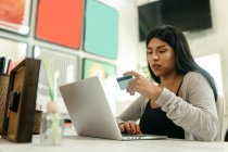 Feminino fazendo compra com cartão de plástico para a ordem durante as compras on-line via laptop — Fotografia de Stock
