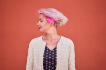 Unbekümmerte Alternative: Frauen werfen gefärbte kurze Haare gegen orangefarbene Wand im Stadtgebiet — Stockfoto