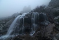 Ефектний вид на водоспади з чистими водяними рідинами на горі під туманним небом восени — стокове фото