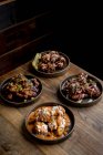 Высокий угол аппетитной хрустящей курицы с соусами, помещенными рядом с крыльями курицы в соусе барбекю, подаваемый с овощами на деревянном столе в ресторане — стоковое фото