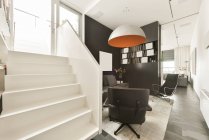 Дизайн інтер'єру вітальні з зручним диваном і шкіряним кріслом в сучасній квартирі з білими і чорними стінами — стокове фото