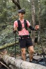 Мужчина-путешественник с треккинговыми палками, стоящими возле озера в лесу — стоковое фото