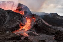 Pittoresca veduta di Fagradalsfjall con fuoco veloce e lava sotto fumo diffuso in montagna con nuvole in Islanda — Foto stock