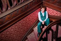 From above of eccentric male actor with smeared makeup sitting on staircase during performance — Stock Photo