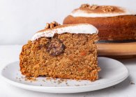 Tasty carrot cake piece with walnut and cinnamon powder on icing sugar glaze on light background — Stock Photo