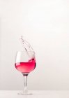 Cristal brillante de vidrio con alcohol cóctel salpicadura rosa sobre fondo blanco en el estudio - foto de stock
