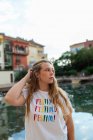 Tranquillo giovane femmina con i capelli lunghi in piedi su argine nella città tropicale in estate sera — Foto stock