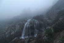 Vista espetacular de cachoeiras com fluidos aquáticos puros no monte sob o céu nebuloso no outono — Fotografia de Stock