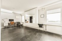 Design de interiores estilo loft contemporâneo de espaçosa área de coworking com cadeiras e mesa com computador no apartamento moderno — Fotografia de Stock