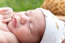 Carino piccolo neonato che dorme mentre giace in una vasca di legno posta sull'erba verde — Foto stock