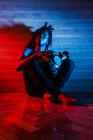 Sonhador preto músico masculino com torso nu tocando tambor africano em estúdio com luzes de néon vermelho e azul — Fotografia de Stock