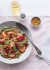 Closeup of a salmon and lentil salad seen from above on a table with a pink tablecloth — Stock Photo