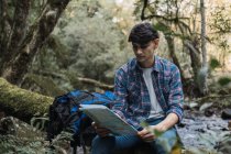 Фокусований чоловічий дослідник читає карту під час пошуку шляху під час походу по джунглях — стокове фото