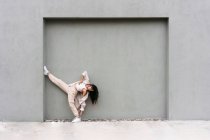 Творческая прохладная женщина опирается на серую стену и танцует выразительно на городской улице — стоковое фото
