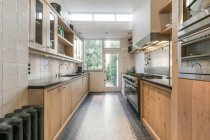 Сучасний інтер'єр просторої кухні з дерев'яними шафами і новою побутовою технікою в квартирі — стокове фото