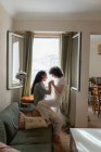 Побічний погляд на зміст ЛГБТ пари закоханих жінок на дивані вдома і дивитися один на одного з любов'ю — стокове фото