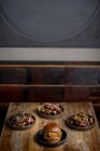 De cima de hambúrguer saboroso com pão frito colocado perto de pratos com asas de frango em molho de churrasco no restaurante — Fotografia de Stock