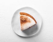 Top view of tasty carrot cake piece with walnut and cinnamon powder on icing sugar glaze on light background — Stock Photo