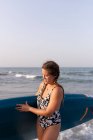 Feminino de maiô de pé com prancha SUP na água do mar no verão e olhando para baixo — Fotografia de Stock