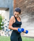 Entschlossene Sportlerin beim Fitnesstraining auf der Stadtstraße im Sommer mit Kurzhanteln — Stockfoto