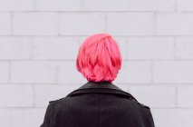 Зворотній перегляд врожаю невизначена жінка з фарбованим волоссям, що стоїть біля білої стіни — стокове фото