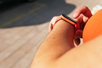 Ernte unkenntliche Sportlerin mit kurvigem Körper beobachtet Herzfrequenz auf tragbarem Tracker während des Trainings auf der Straße — Stockfoto