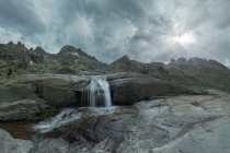 Scenic view of Sierra de Gredos with cascade and pond under cloudy sky — Stock Photo