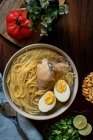 Dall'alto di appetitoso brodo di pollo fresco con ingredienti assortiti serviti in ciotola sul tavolo in cucina — Foto stock