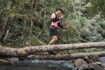 Чоловік мандрівник з палицями, що стоять біля озера в лісі — стокове фото