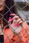 Vista di raccolto di mano di femmina elegante con manicure lunga luminosa in piedi vicino a recinzione in metallo — Foto stock