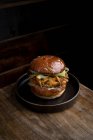 Dall'alto di hamburger saporito con panini fritti e verdure servite su piatto e messe su tavolo di legno in ristorante — Foto stock