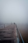 Unrecognizable person strolling on wooden quay into thick fog in morning in Lisbon, Portugal — Stock Photo