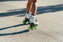 Cortada fêmea ajuste irreconhecível em patins mostrando acrobacias na estrada na cidade no verão — Fotografia de Stock