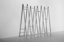 Black and white of ladders against smooth wall with shadow in light room during improvement process at home — Stock Photo
