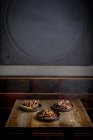 Conjunto de deliciosas asas de frango grelhado em molho de churrasco servido com legumes em pratos redondos e colocado em mesa de madeira no restaurante — Fotografia de Stock