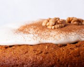 Close-up of tasty carrot cake with walnut and cinnamon powder on icing sugar glaze on light background — Stock Photo