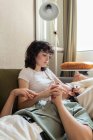 Tierna mujer lesbiana tumbada sobre las rodillas de la novia amorosa sentada en el sofá en casa y relajada durante el fin de semana - foto de stock