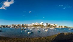 Vista de olho de peixe de muitos barcos flutuando na ondulação da água do rio perto da cidade contra o céu azul nublado em Fuerteventura, Espanha — Fotografia de Stock