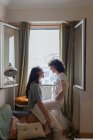 Вид сбоку на содержание ЛГБТ пара влюбленных женщин на диване дома и смотрят друг на друга с любовью — стоковое фото