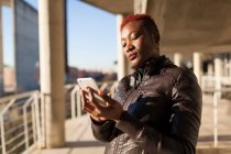 Seitenansicht der schönen Afro-Frau, die mit ihrem Smartphone kommuniziert — Stockfoto