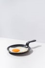 Delicioso ovo frito na frigideira preta servida na mesa no fundo branco no estúdio — Fotografia de Stock
