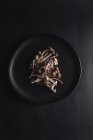 Top view of fresh shimeji mushrooms served on black plate on dark table in studio — Stock Photo