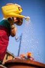 Знизу зріла жінка поливає квіти в сонячний день — стокове фото