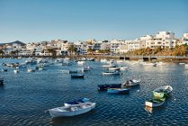 Many boats floating on rippling river water near town against cloudy blue sky in Fuerteventura, Spain — Stock Photo