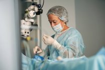 Доросла жінка-лікар у хірургічній формі та стерильній масці сидить у клініці — стокове фото