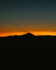 Paisagem de tirar o fôlego de silhueta de gama montesa no fundo de céu de pôr-do-sol cor-de-laranja brilhante — Fotografia de Stock