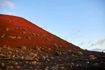 Rocce rocciose e arbusti secchi situati vicino al pendio della collina contro il cielo blu nuvoloso al mattino a Fuerteventura, Spagna — Foto stock