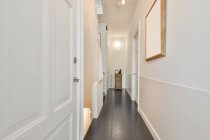 Perspective view of empty narrow hallway with white doors and walls in modern apartment — Stock Photo